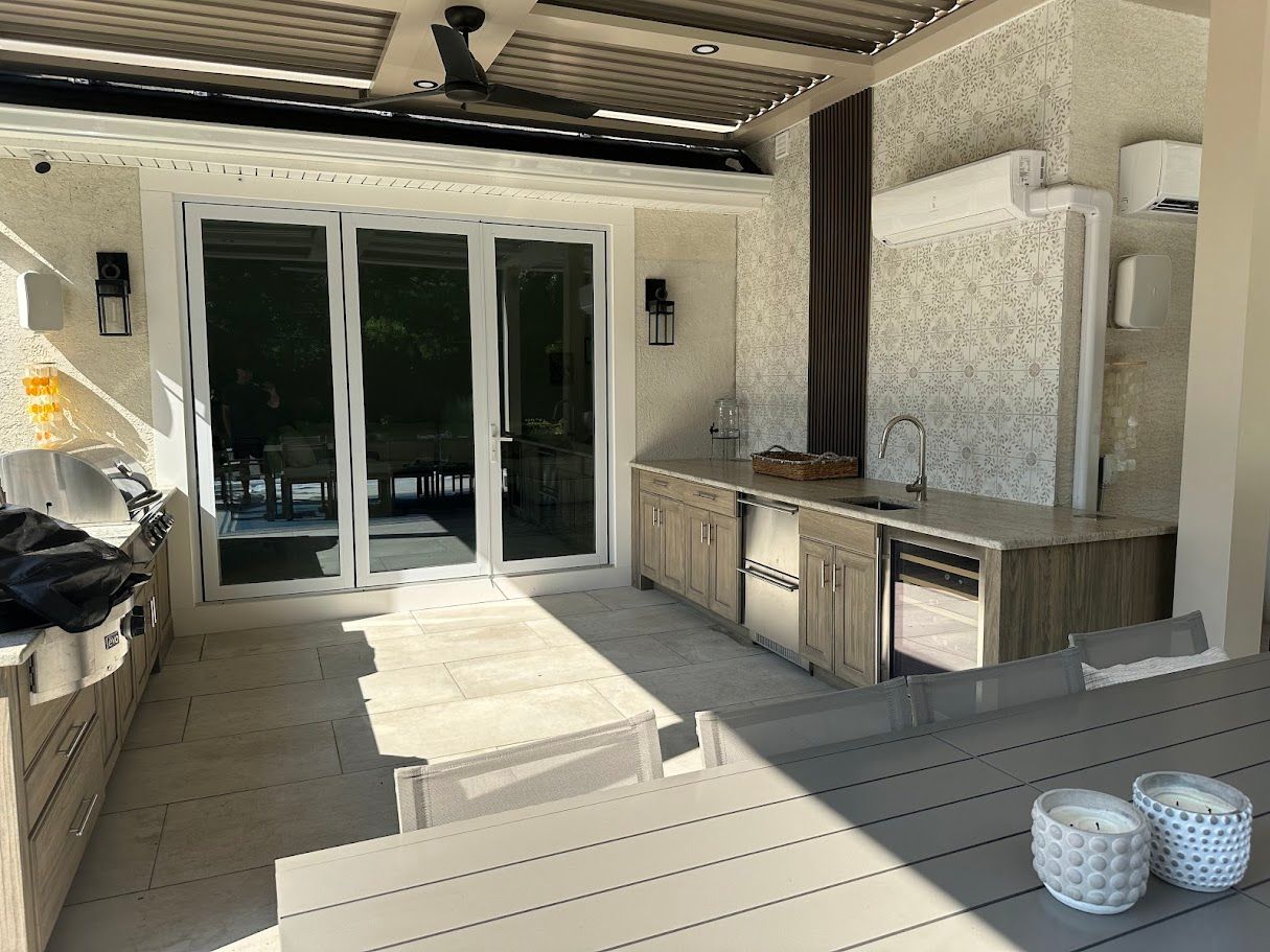 Covered outdoor kitchen with cabinets, appliances, and a dining table.