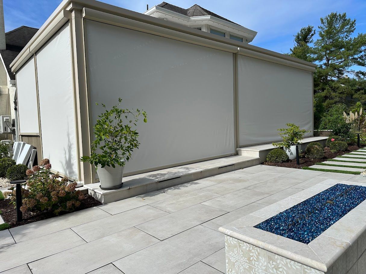 Outdoor patio with large white shades, stone patio, and fire pit.