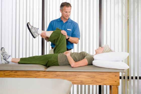 Physical therapist stretching a patient’s leg on a treatment table in a clinic