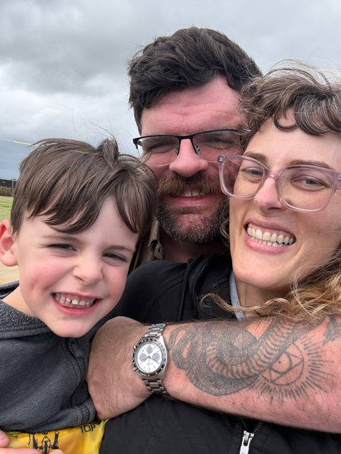 Becker Family huddled together outdoors under a cloudy sky.