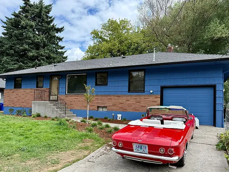 Blue house with red brick accents, red convertible in driveway.