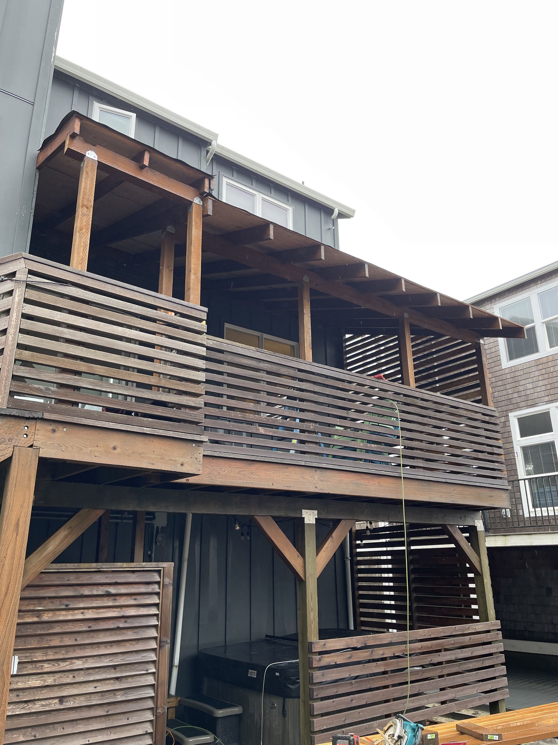 Wooden two-story building with slatted balcony and open lower level, viewed from below
