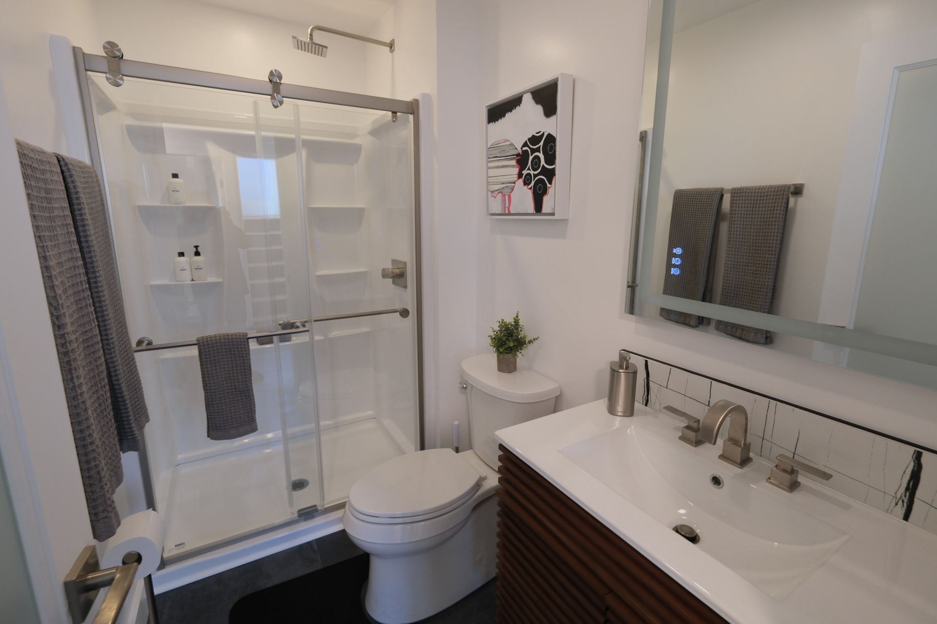 Bright bathroom with glass shower, white vanity, and mirror above sink.