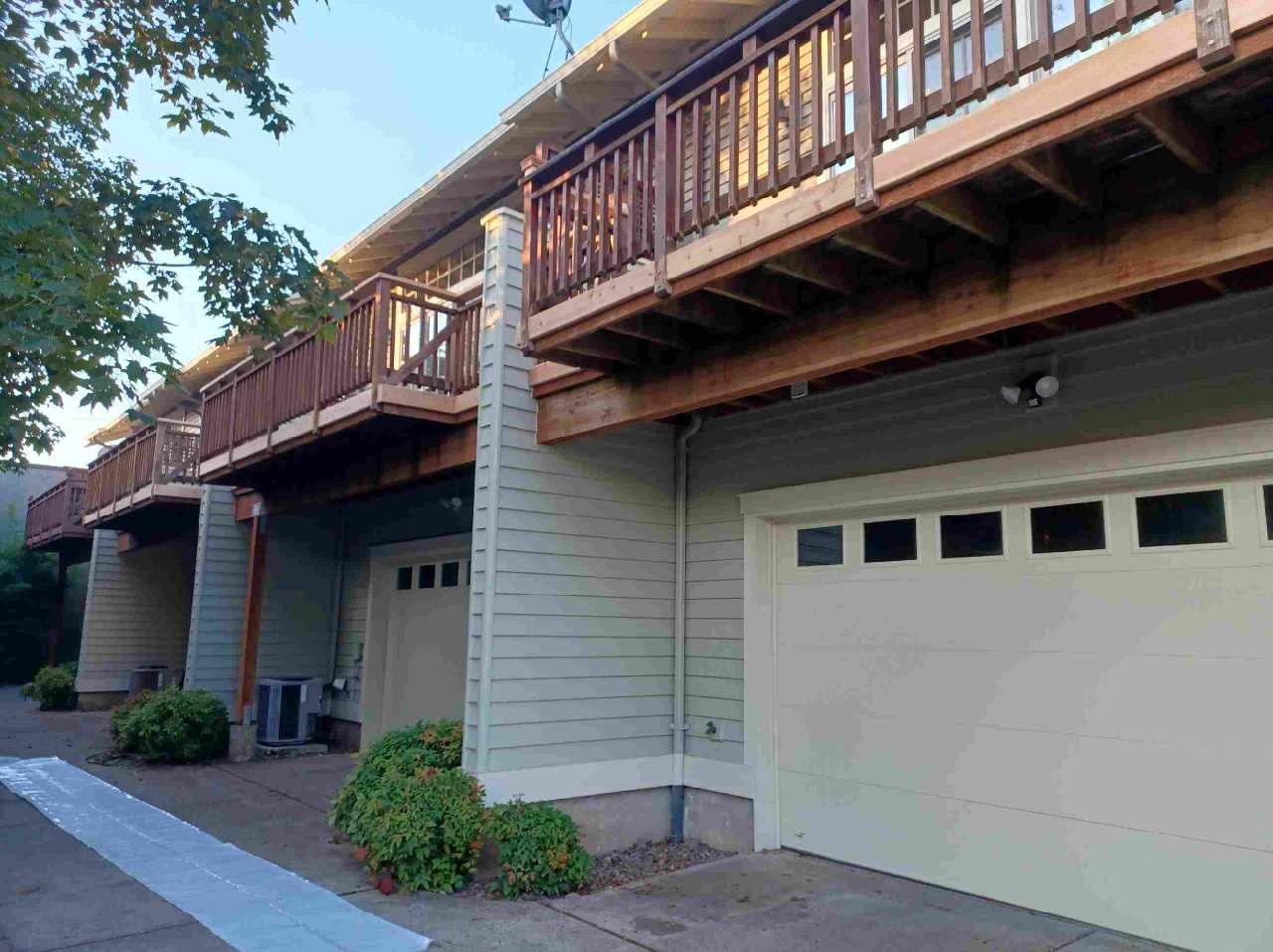 Row of garage doors beneath wooden balconies on a residential building at dusk
