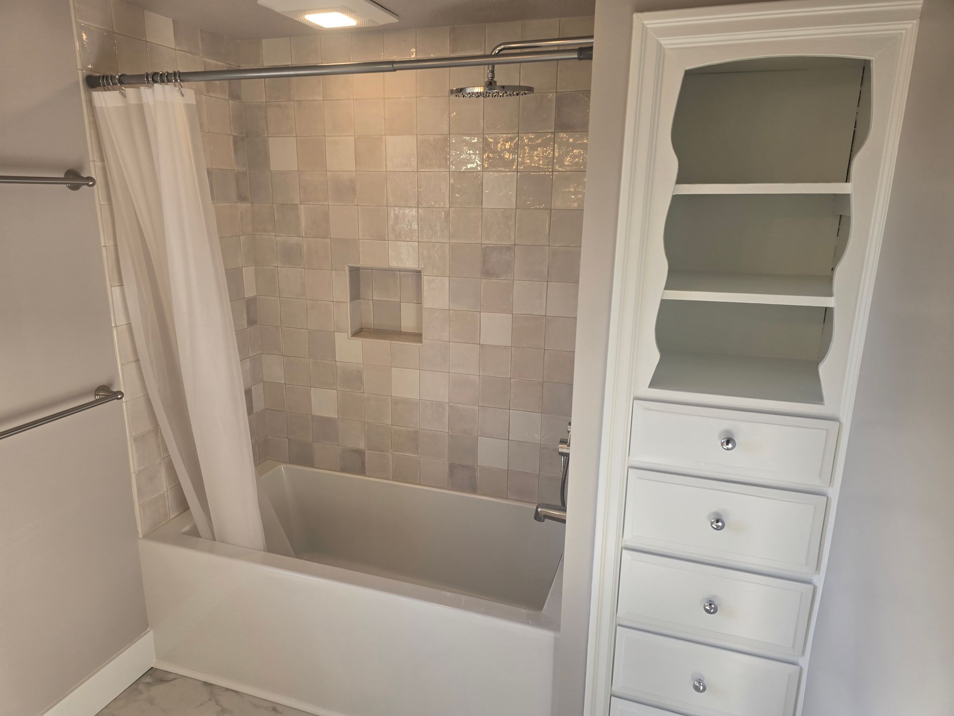 Bathroom with tiled shower, tub, shower curtain, and white built-in shelving cabinet.