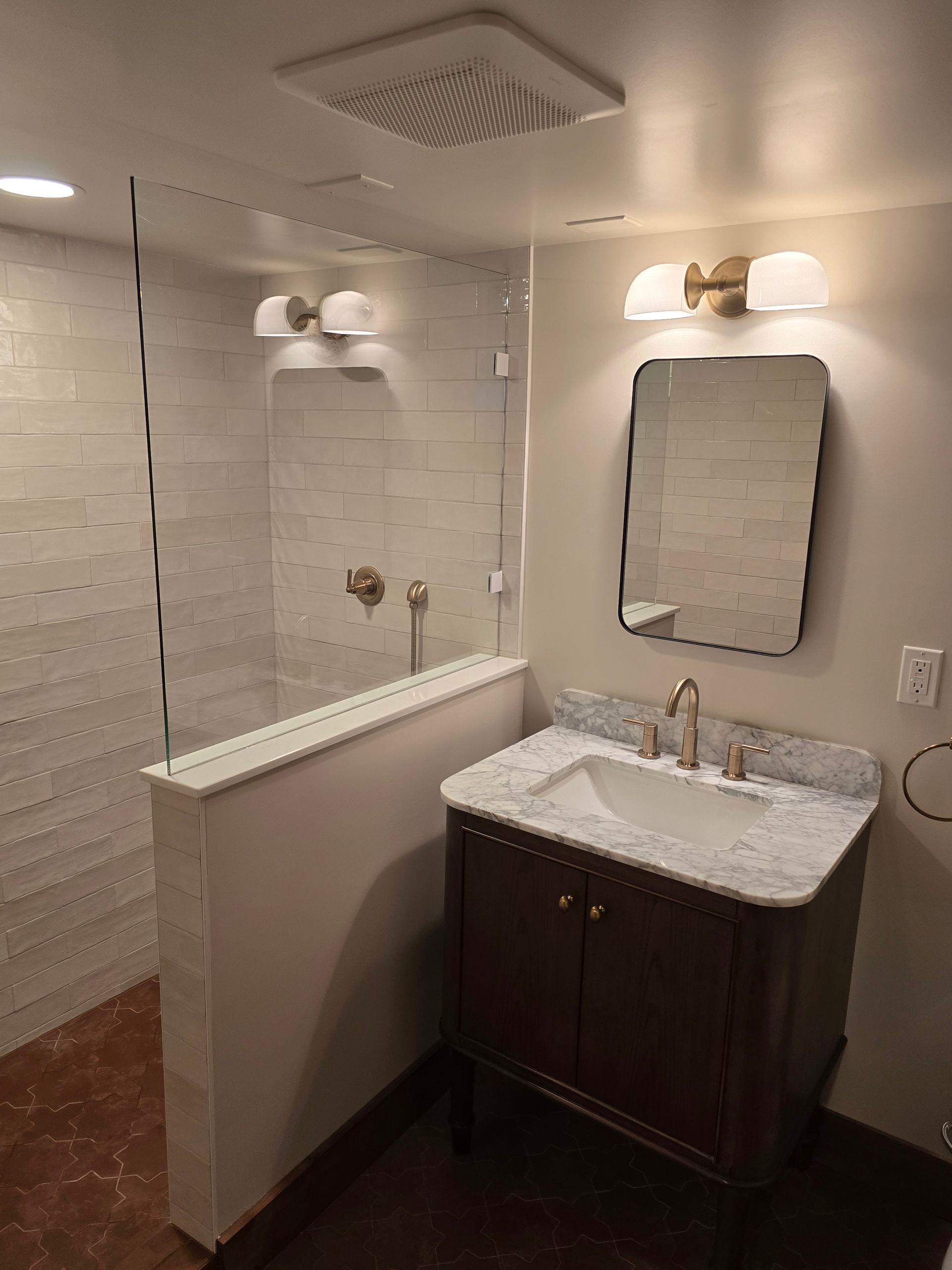 Small bathroom with a vanity sink, mirror, and partitioned toilet/shower area.
