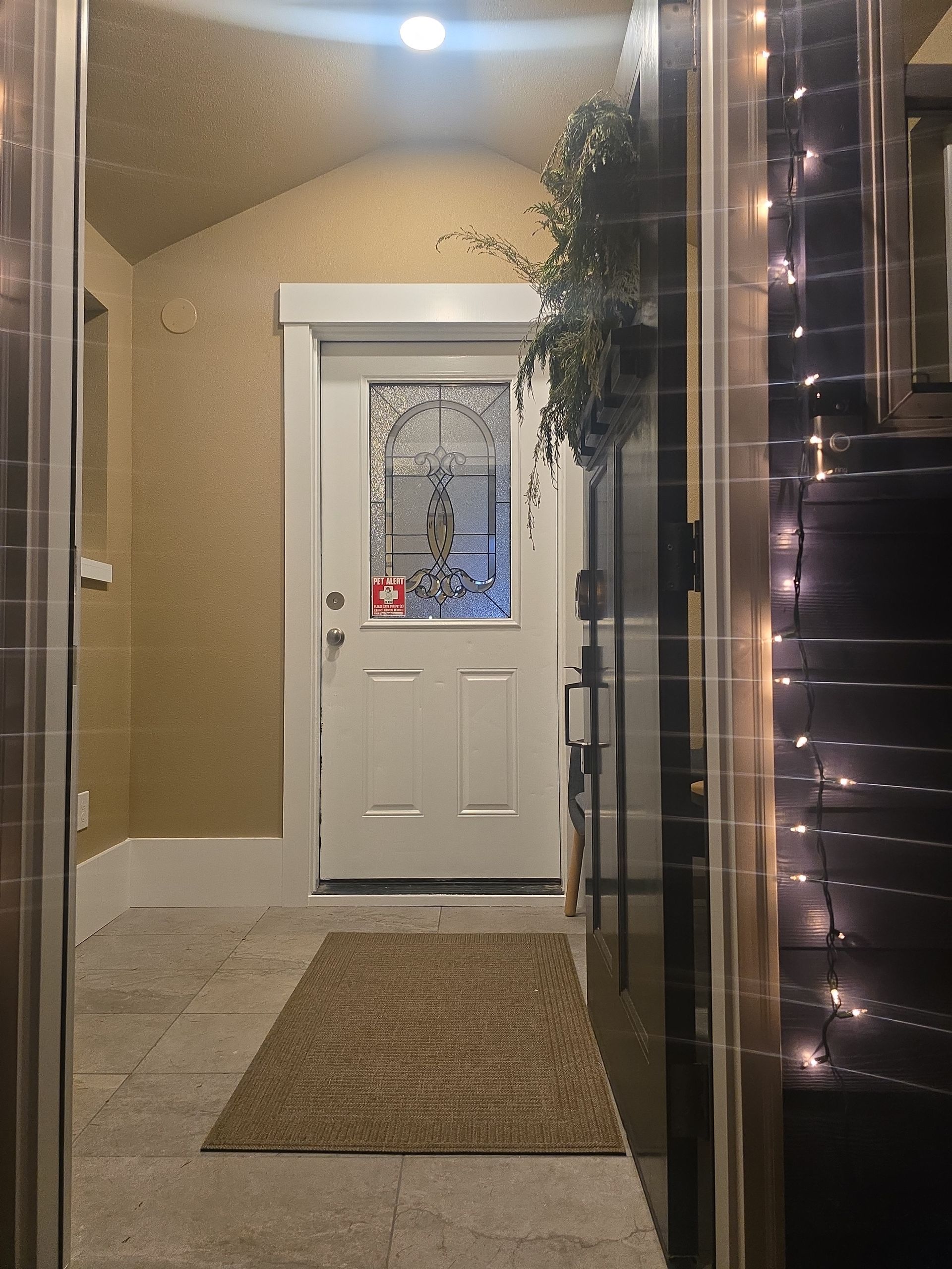 Front porch with a white front door, beige walls, rug, and string lights at night.