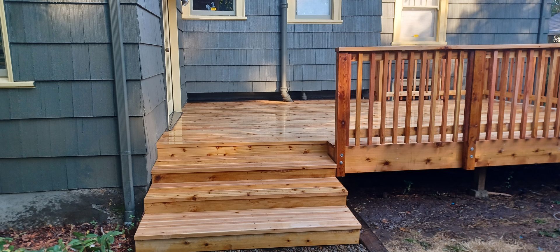 Wooden steps leading to a blue house porch with a railing on the right