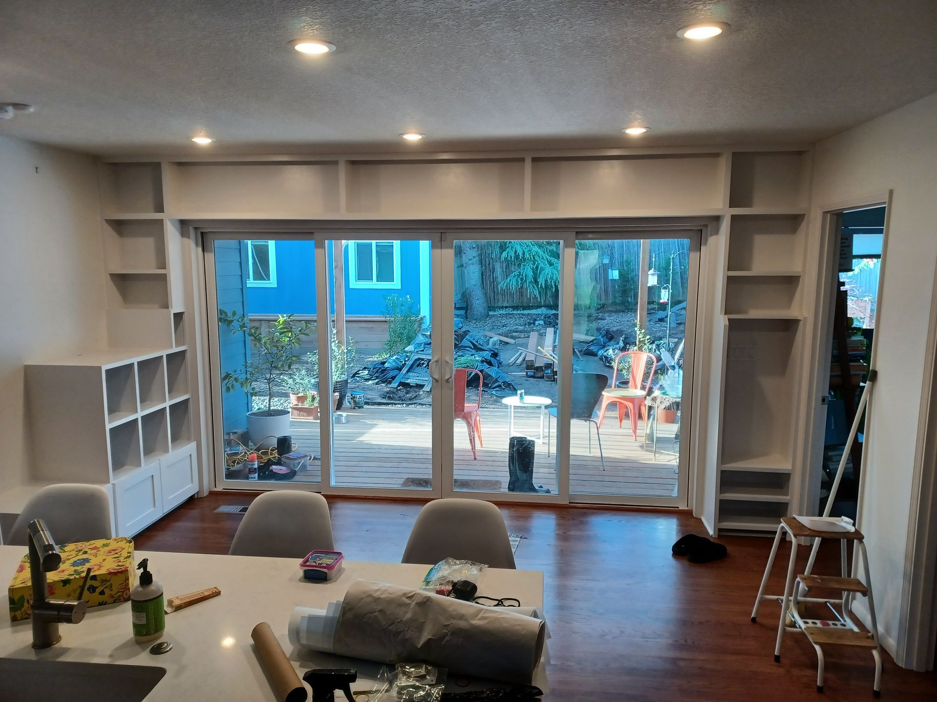 Modern living room with built-in shelves, sliding glass doors, dining table, and patio view