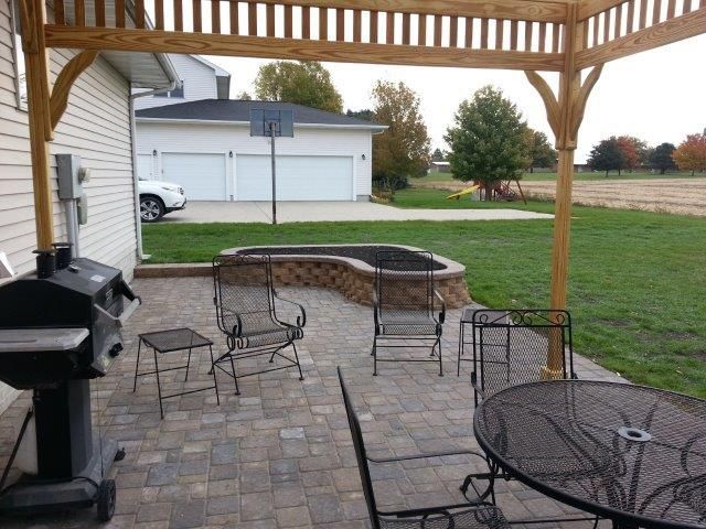A patio with a grill and chairs under a pergola