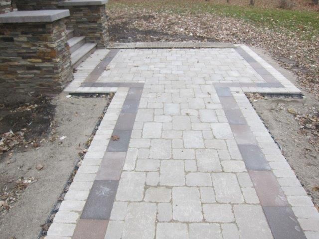 A brick walkway with a stone wall on the side