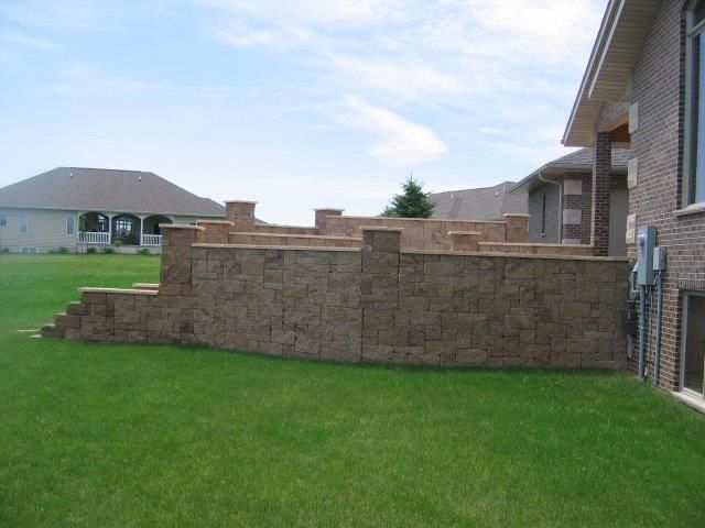 A large brick wall is in the backyard of a house.