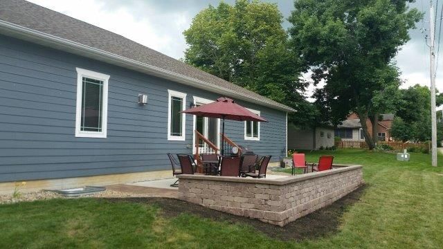 A blue house with a patio and umbrella in front of it.