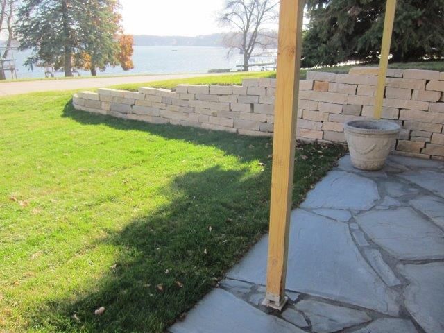 A stone patio with a view of a lake