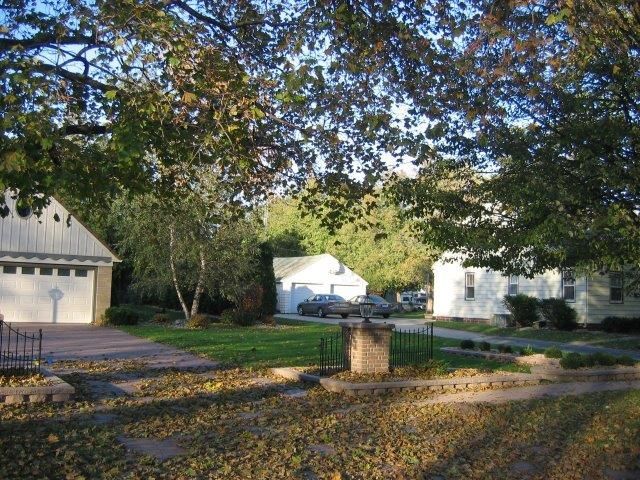 A house with a white garage door is surrounded by trees