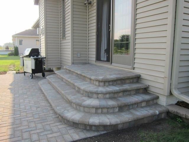 A house with stairs and a grill in front of it.