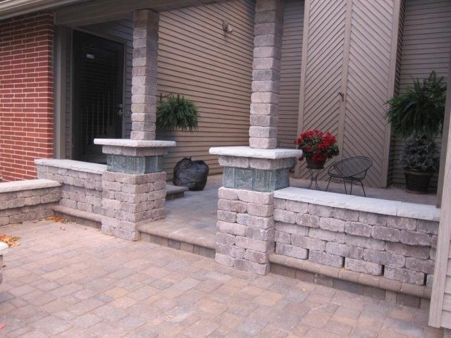 A porch with a brick wall and pillars in front of a brick house