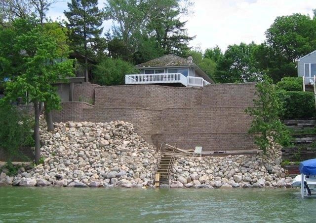 A house is sitting on top of a rocky hill next to a body of water.