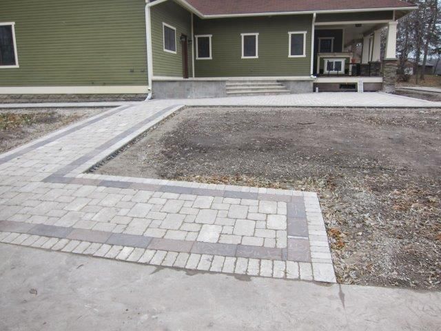 A green house with a brick walkway leading to it
