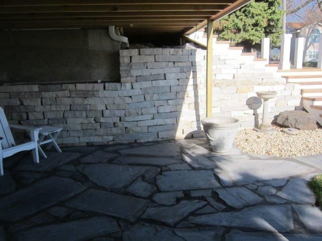 A stone patio with a white chair and a brick wall