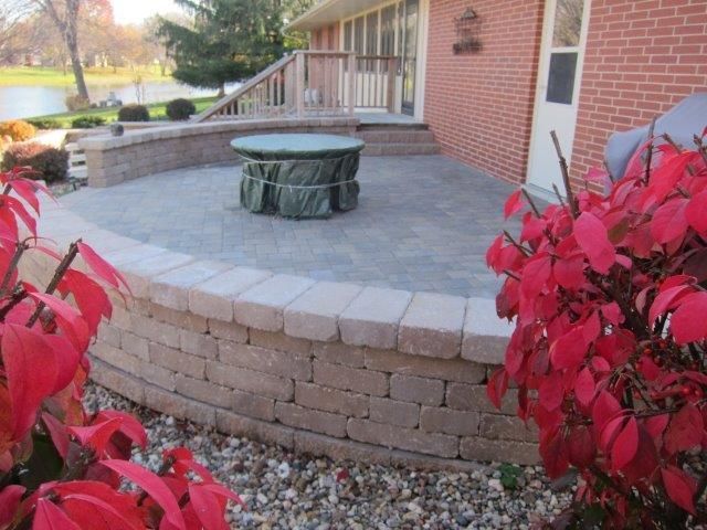 A brick patio with a table and red leaves in front of a brick house