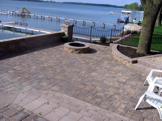 A patio with a fire pit and chairs overlooking a lake