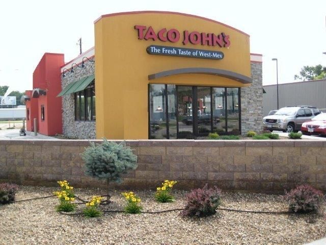 A taco john 's restaurant with cars parked in front of it