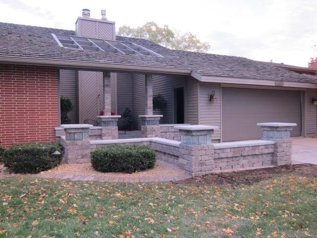 A brick house with a driveway and a brick wall in front of it.
