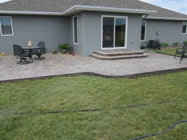 A patio with a table and chairs in front of a house.