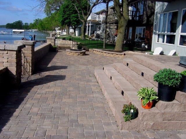 A patio with steps leading up to a house with a lake in the background