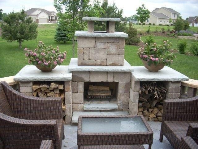 A patio with a fireplace and chairs and a table