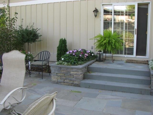 A patio with chairs and a potted plant in front of a house