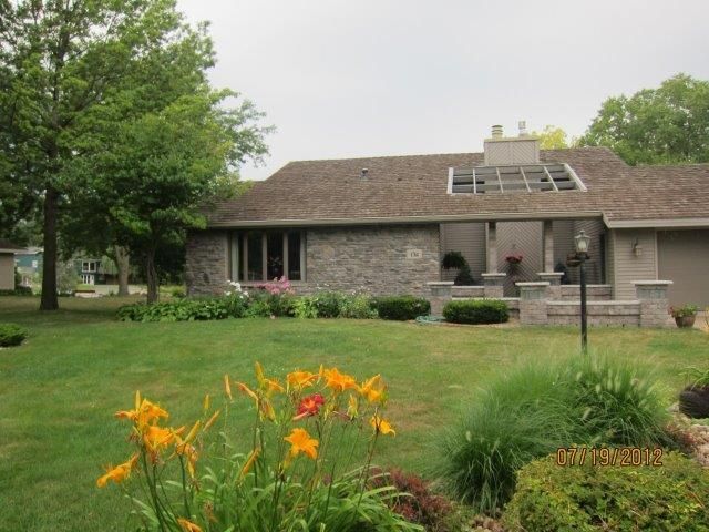 A house with a large lawn and flowers in front of it
