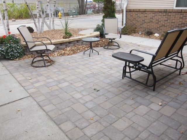 A patio with chairs and a table in front of a house