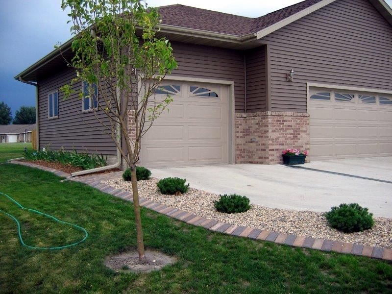 A house with two garage doors and a tree in front of it