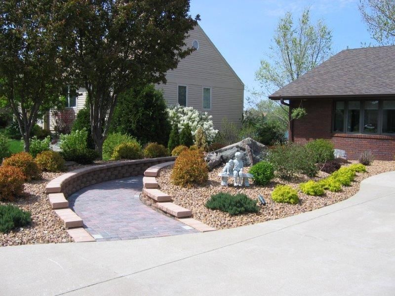 A driveway leading to a house with a lush green garden