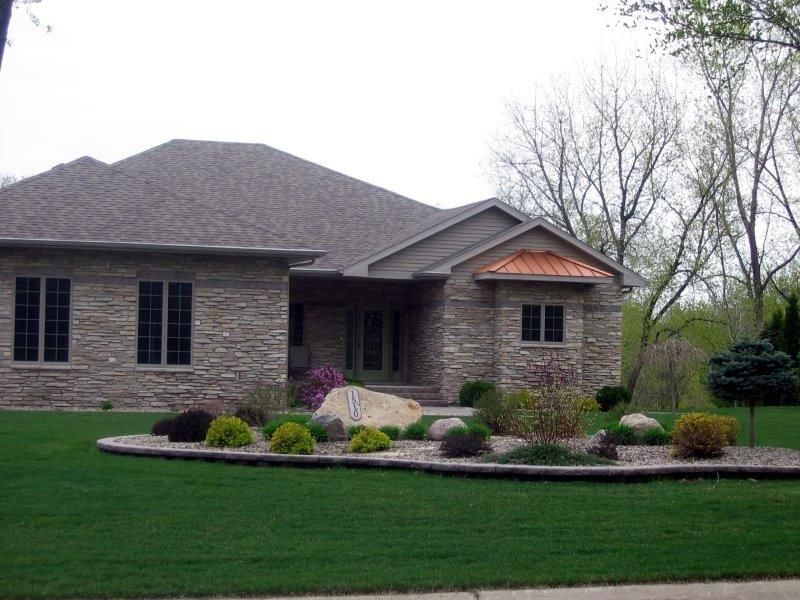 A large stone house with a lush green lawn in front of it