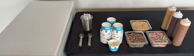 A table topped with cups, bottles, spoons and condiments.
