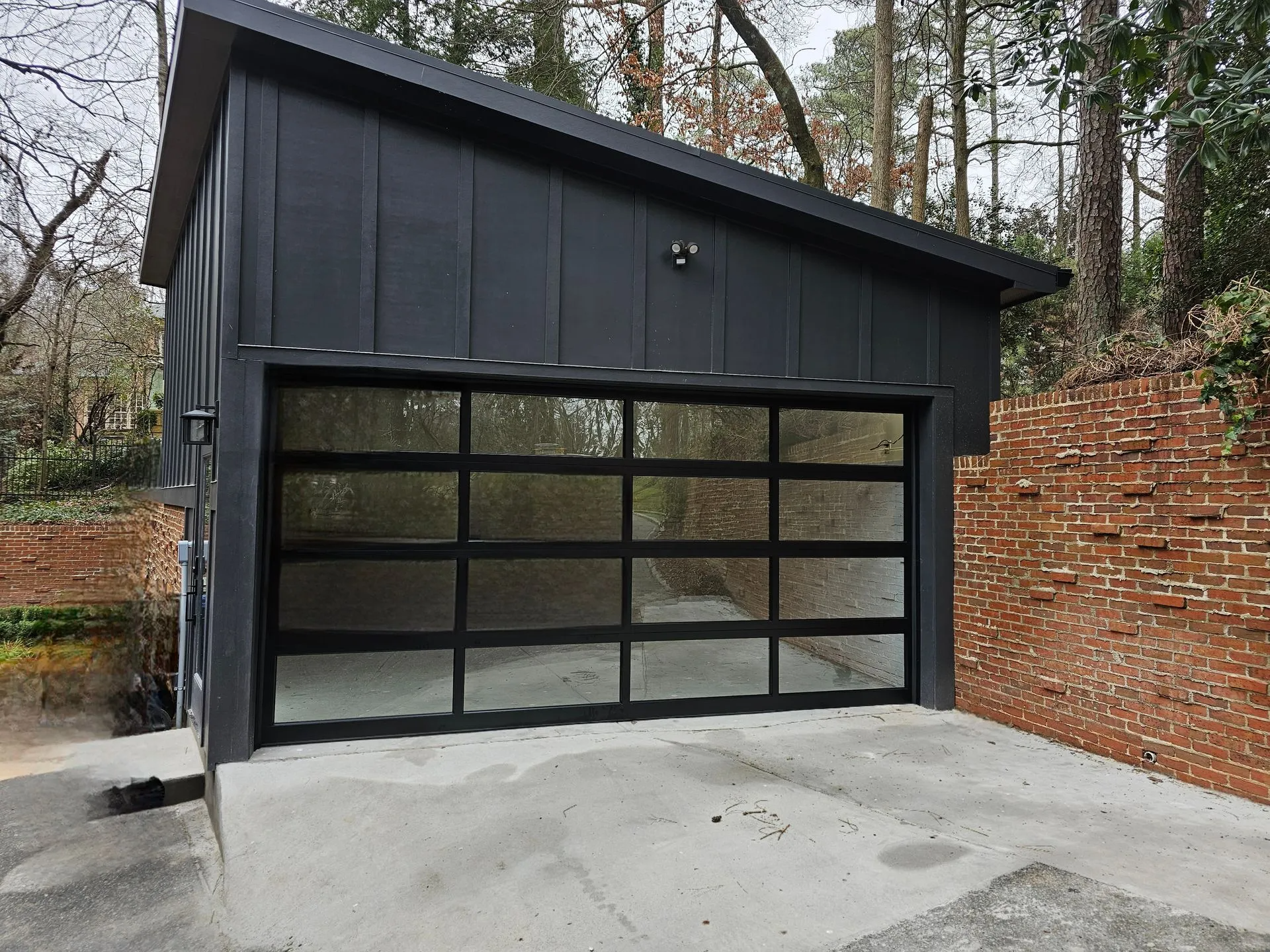 A black garage with a glass door and a brick wall.