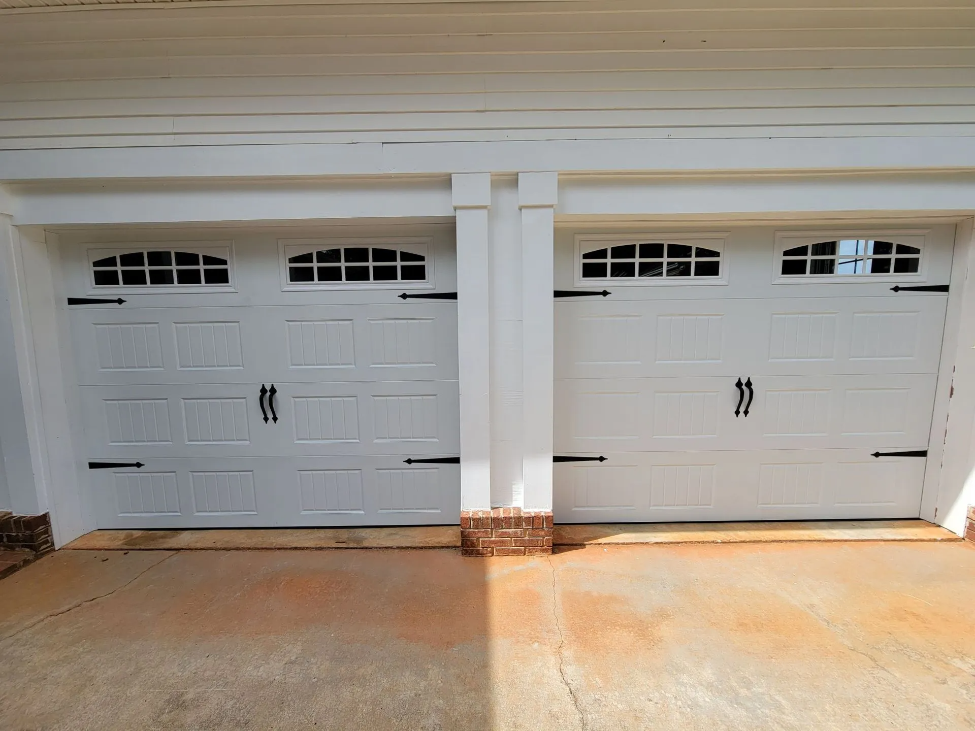 There are two white garage doors on the side of a house.