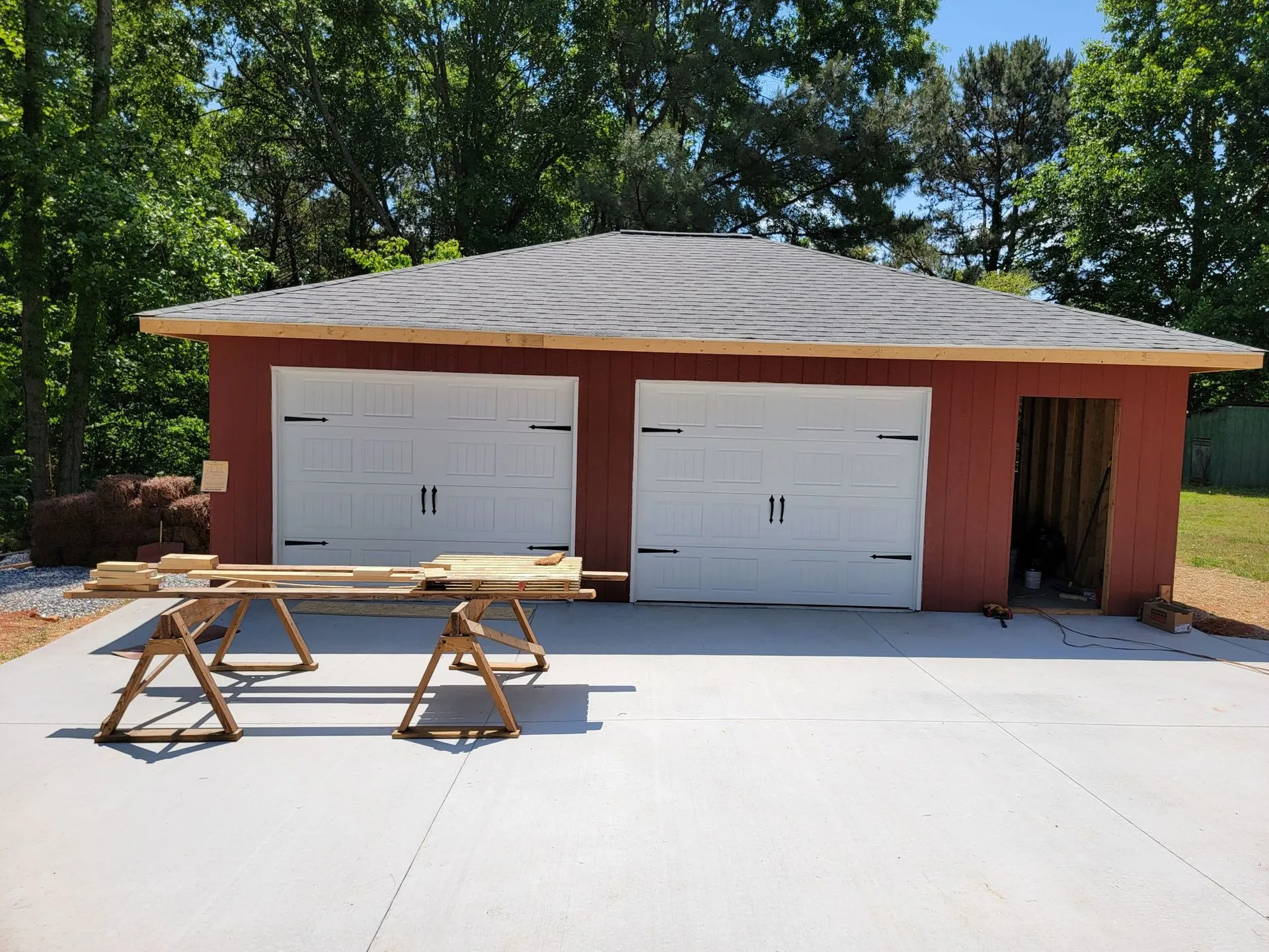 A red garage with two white garage doors is being built.