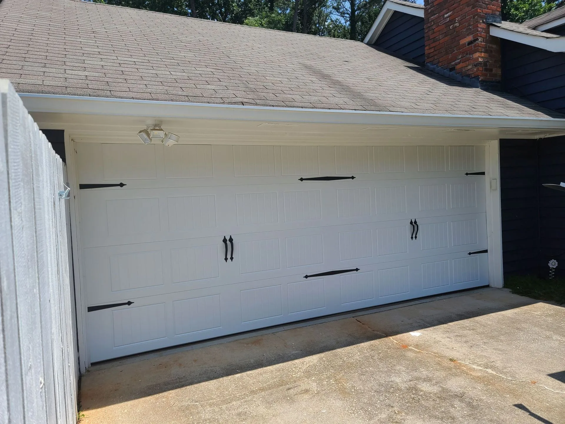 A white garage door is sitting next to a black fence.