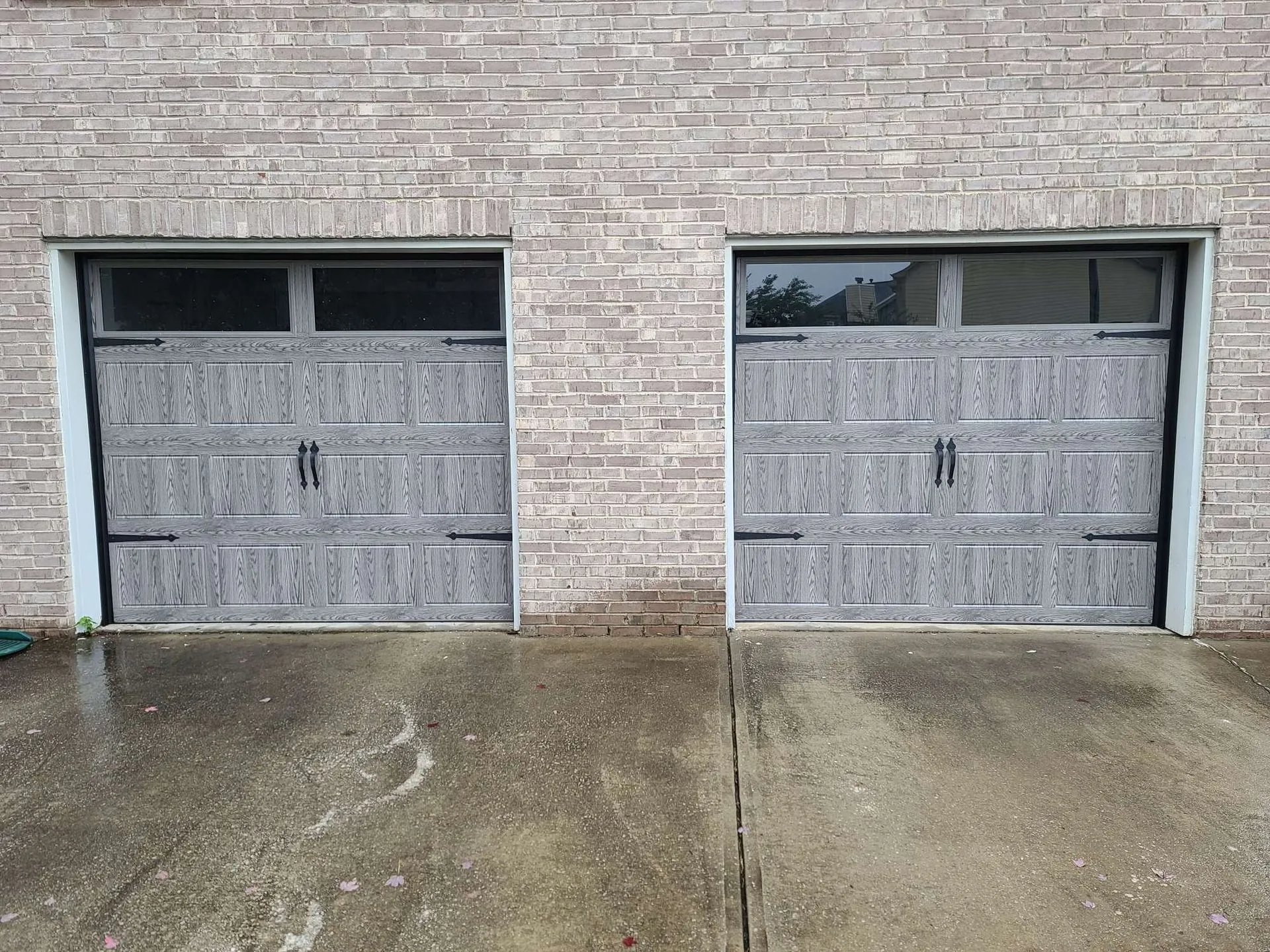 Two garage doors are sitting next to each other on a brick building.