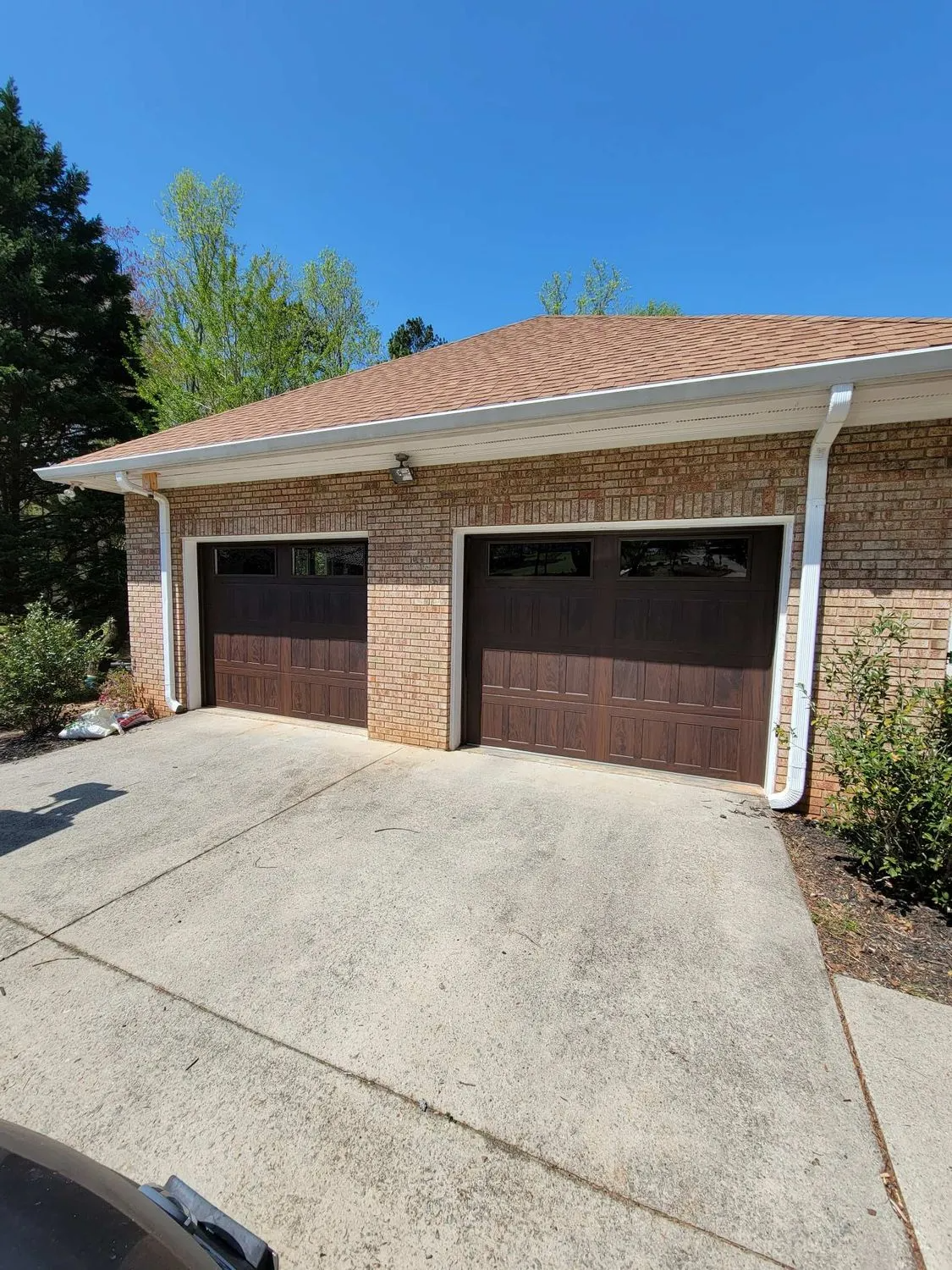 A brick house with two garage doors and a driveway.