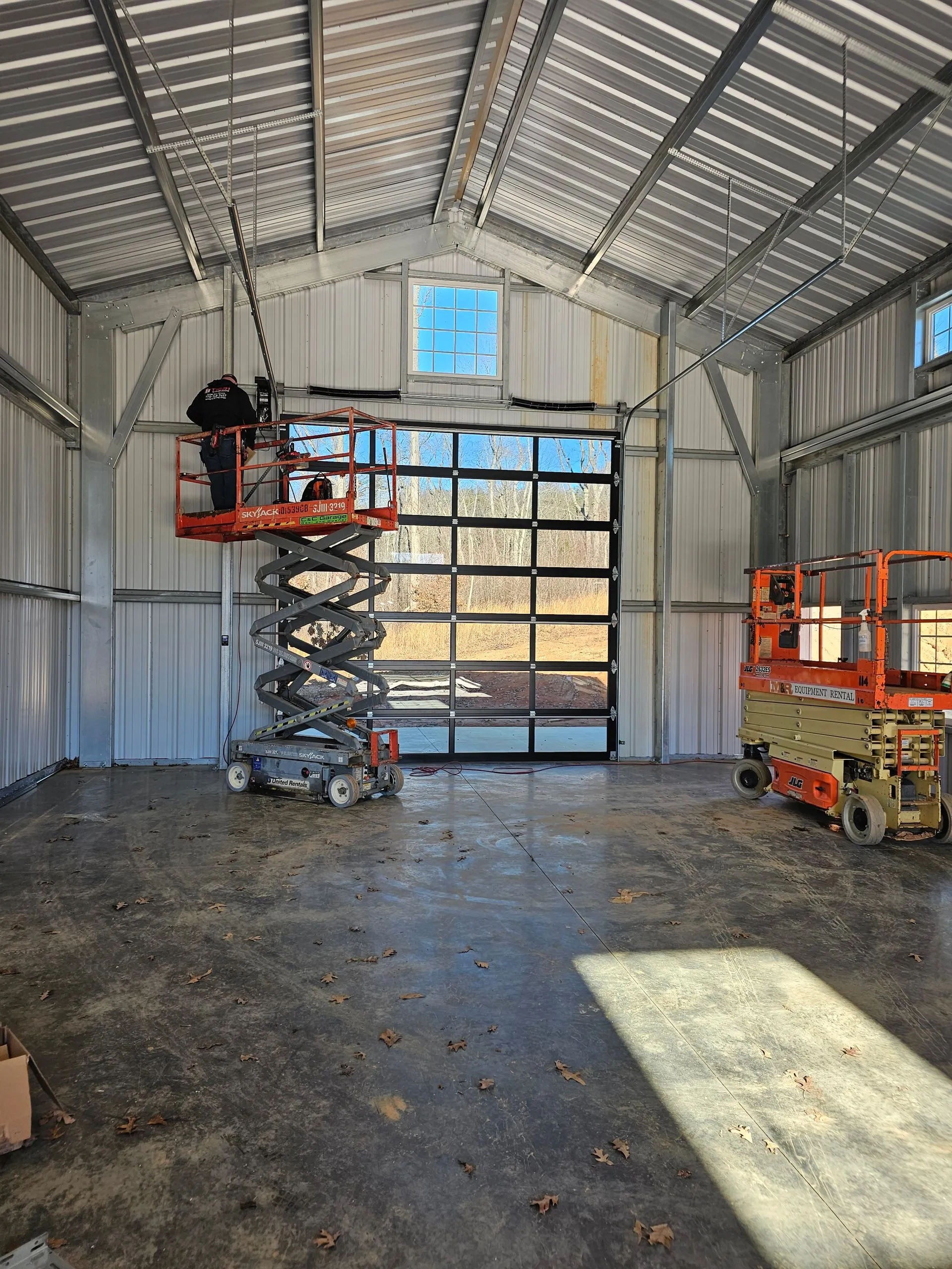 A man on a scissor lift is working on a garage door.