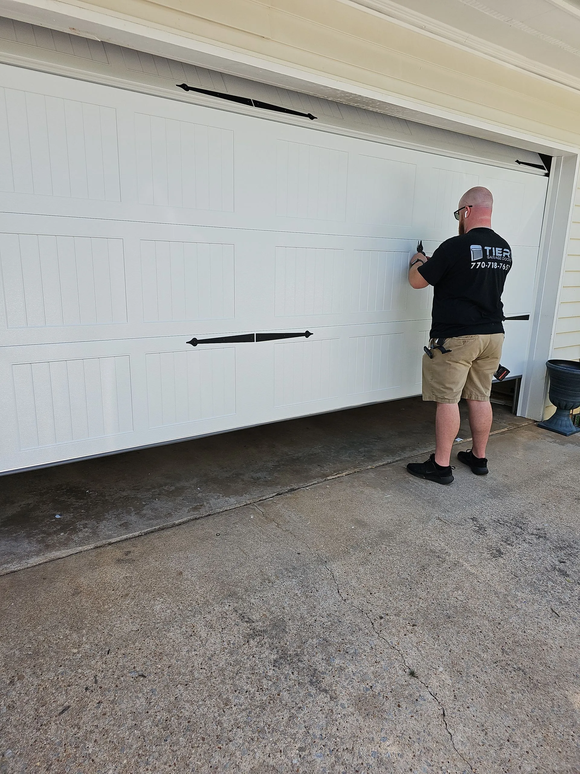 A man is standing in front of a white garage door.