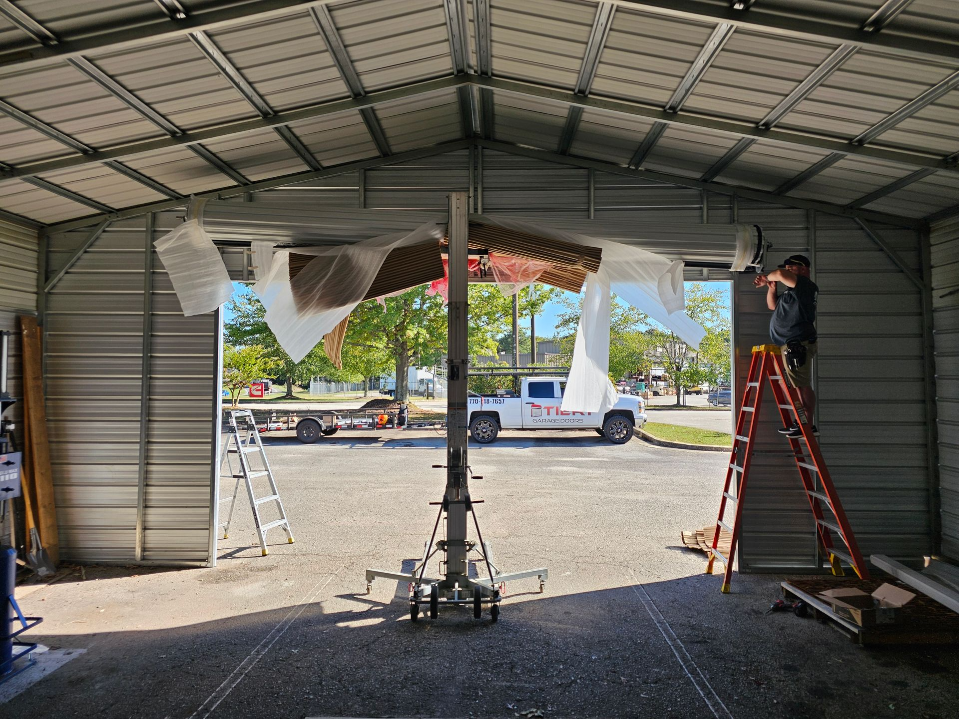 A man is standing on a ladder in a garage.