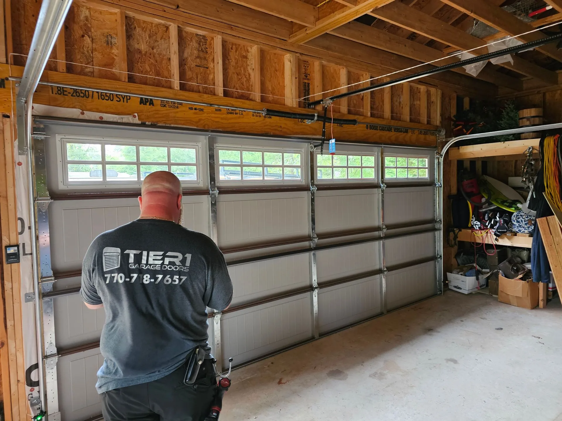 A man is standing in a garage looking at a garage door.