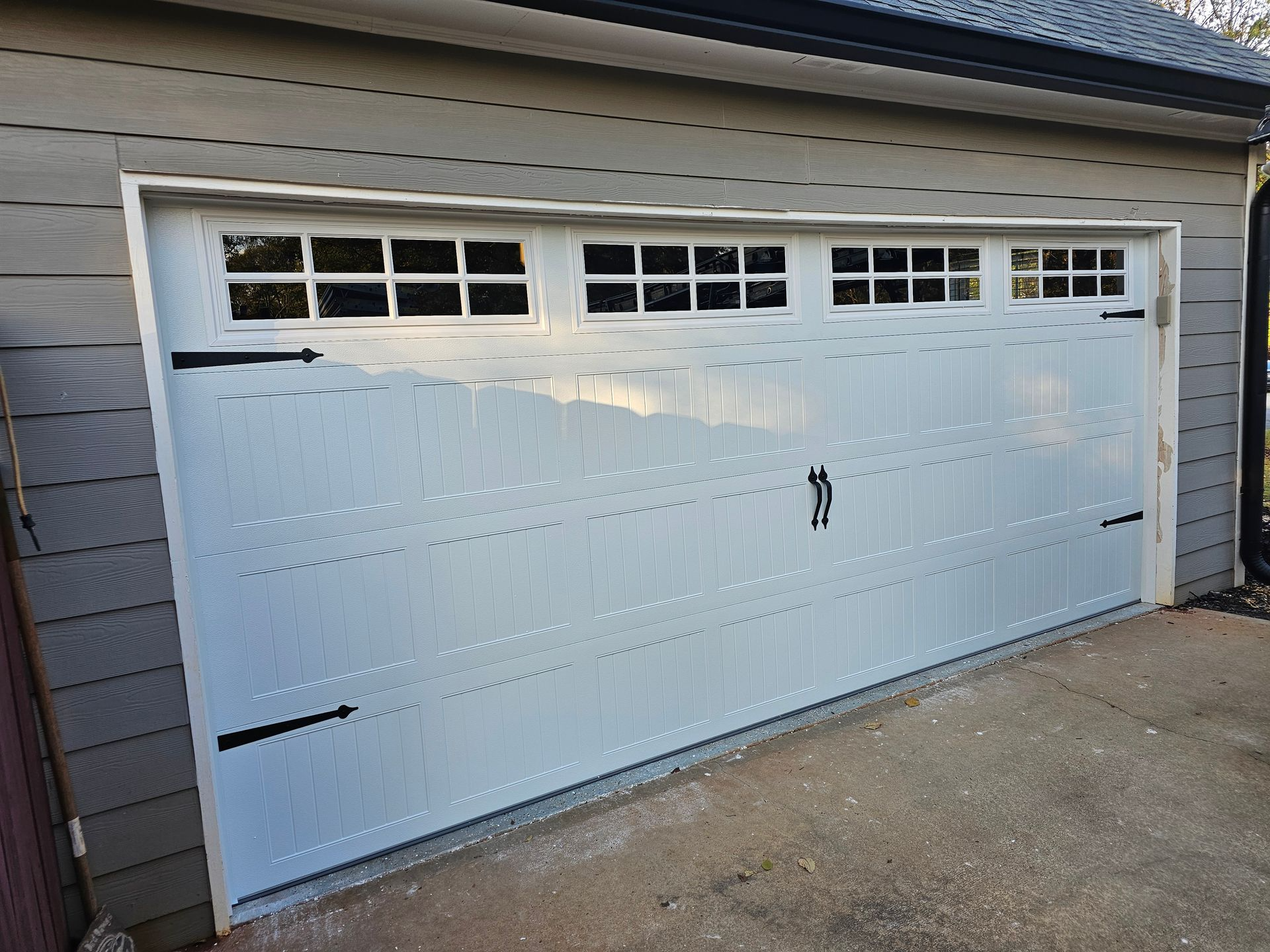 A white garage door is sitting on the side of a house.