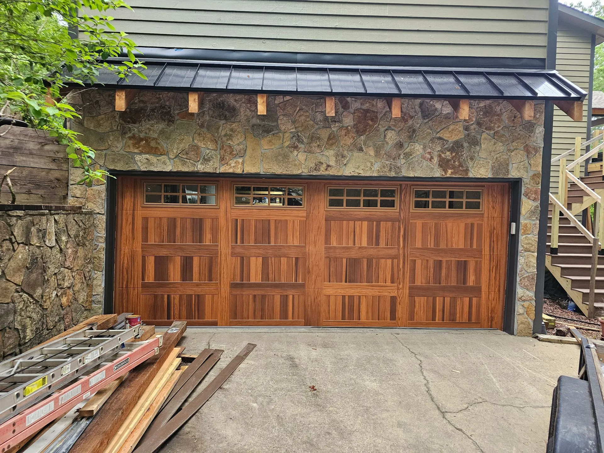 A wooden garage door is being installed on the side of a house.